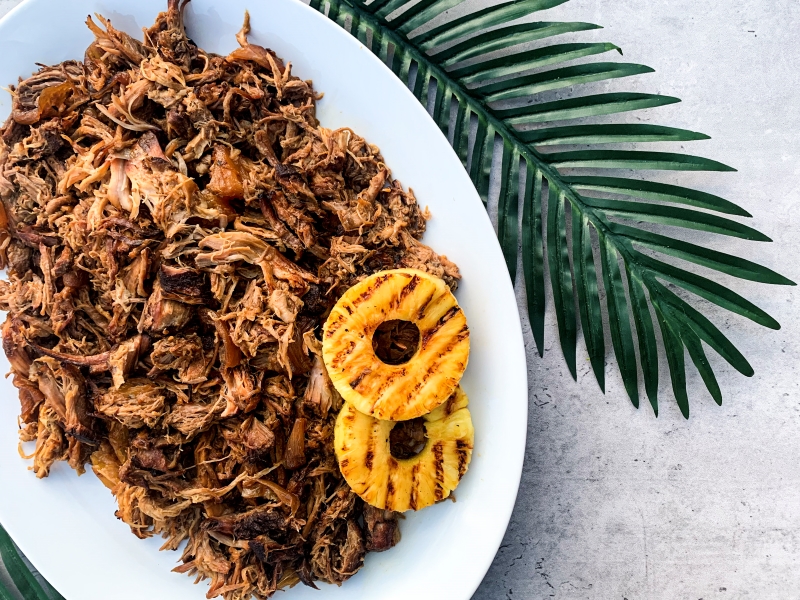 Hawaiian Pulled Pork  n a white oven plate with 2 grilled pineapple rings. 