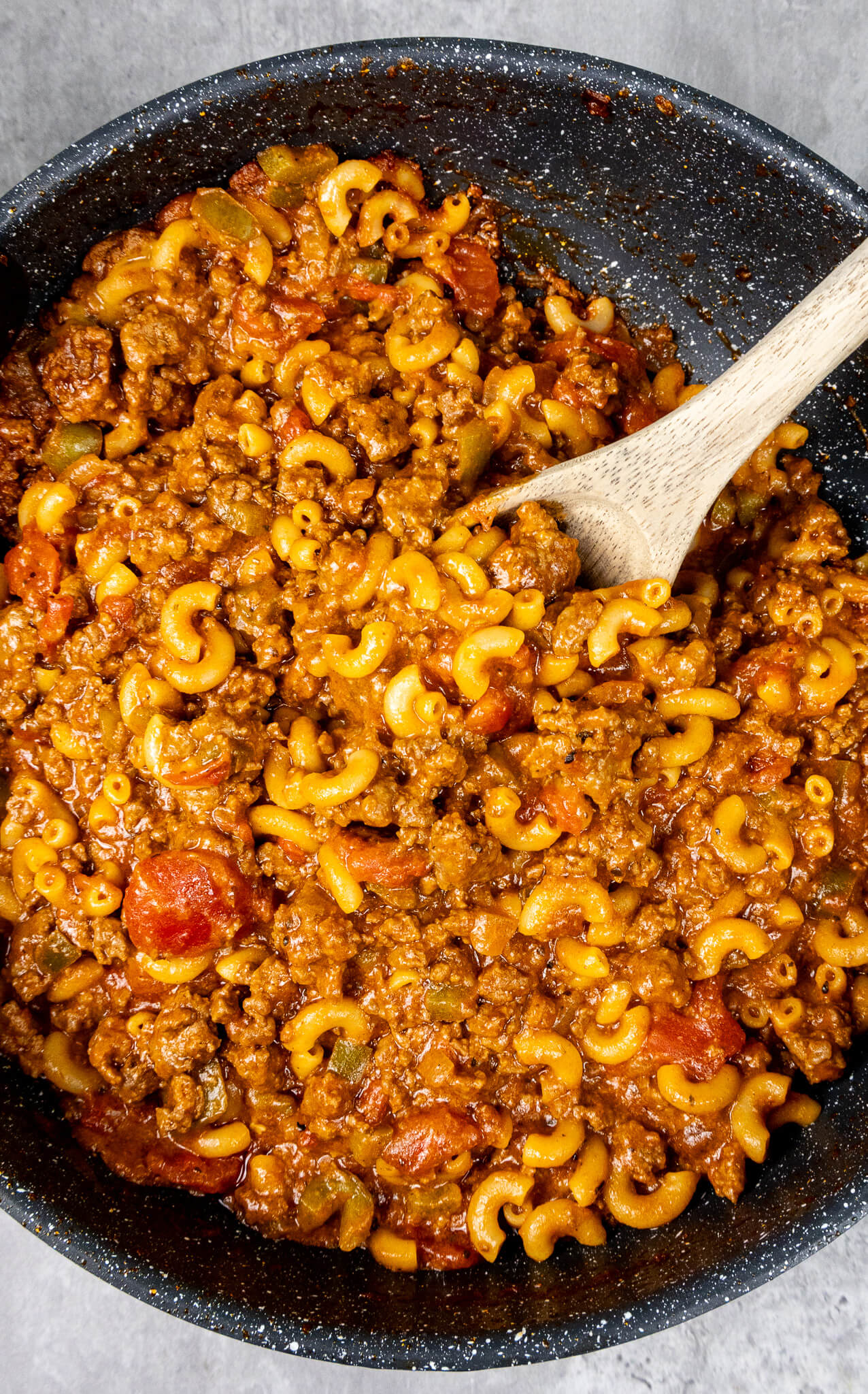 One-Pot Classic American Goulash in a pan with a wooden spoon scooping a portion 