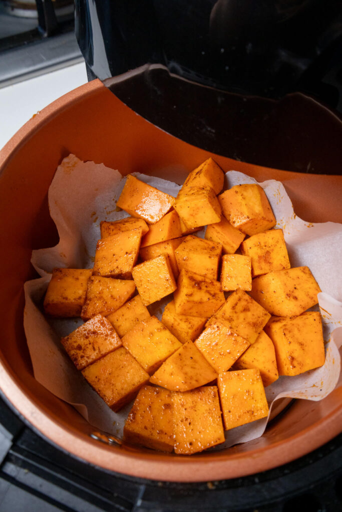 cubed sweet potatoes covered in spices in an air fryer