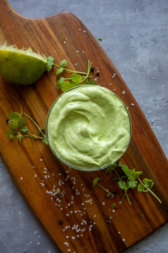 avocado crema in a bowl on top of a wooden cutting board 