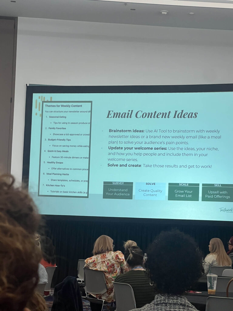 Conference room with a presentation displayed on a large screen. The slide titled Email Content Ideas lists themes and tips for weekly newsletters. Attendees, seated at tables, are focused on the presentation.