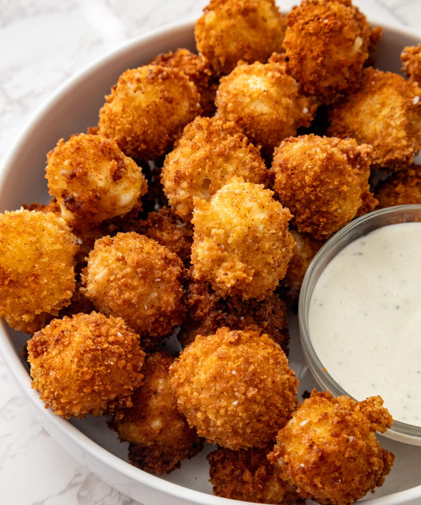 A round serving platter with crispy Nashville Hot Mozzarella Bites and ranch dipping sauce. 