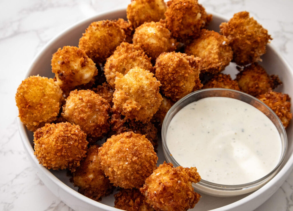 A plate of crispy Nashville Hot Mozzarella Bites with ran dipping sauce. 