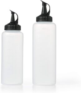 Two clear plastic squeeze bottles with black caps, one taller and one shorter, stand upright on a white surface. Both have cone-shaped tops for precise dispensing. The background is plain white.