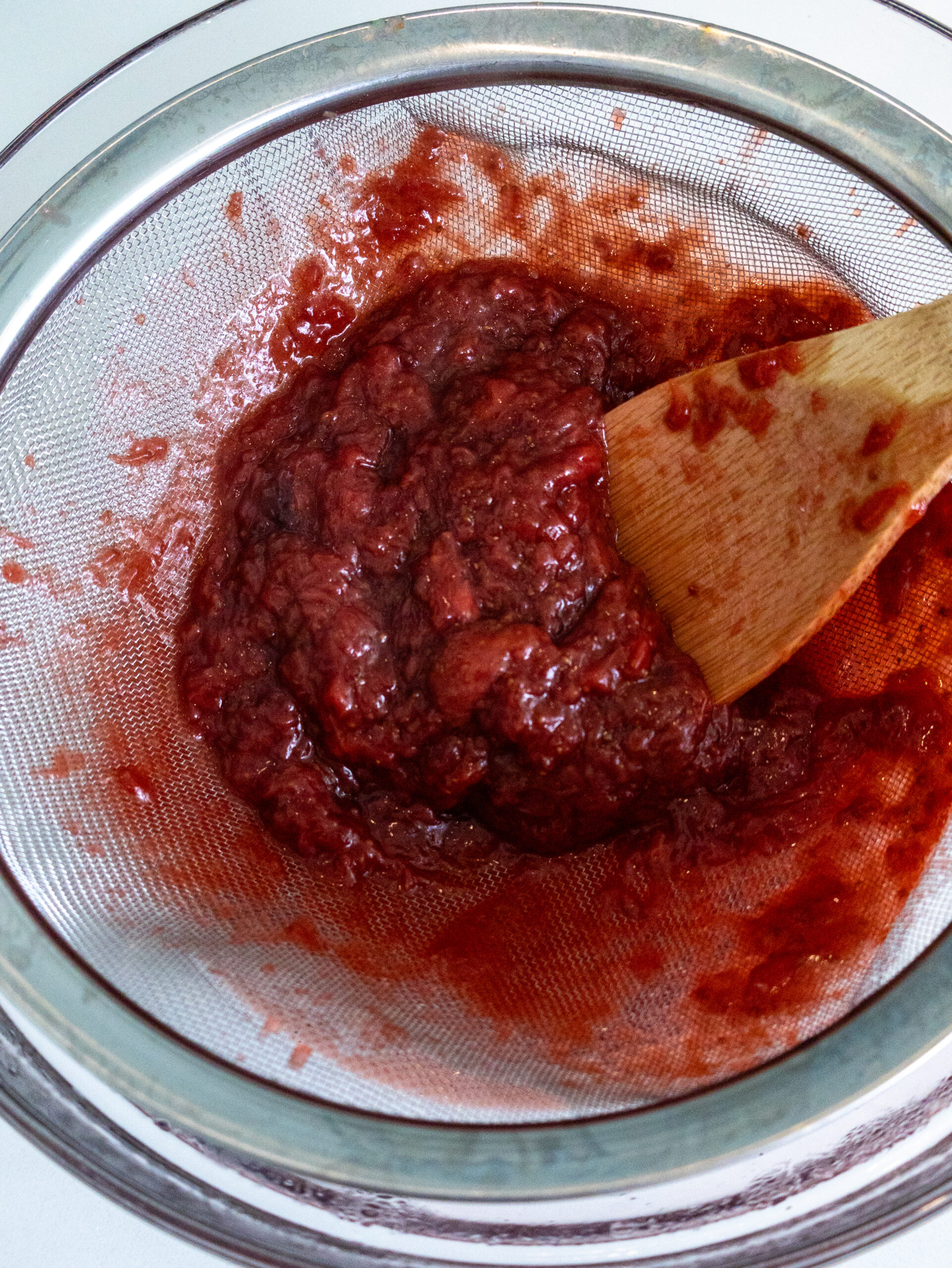 macerated strawberries in a strainer