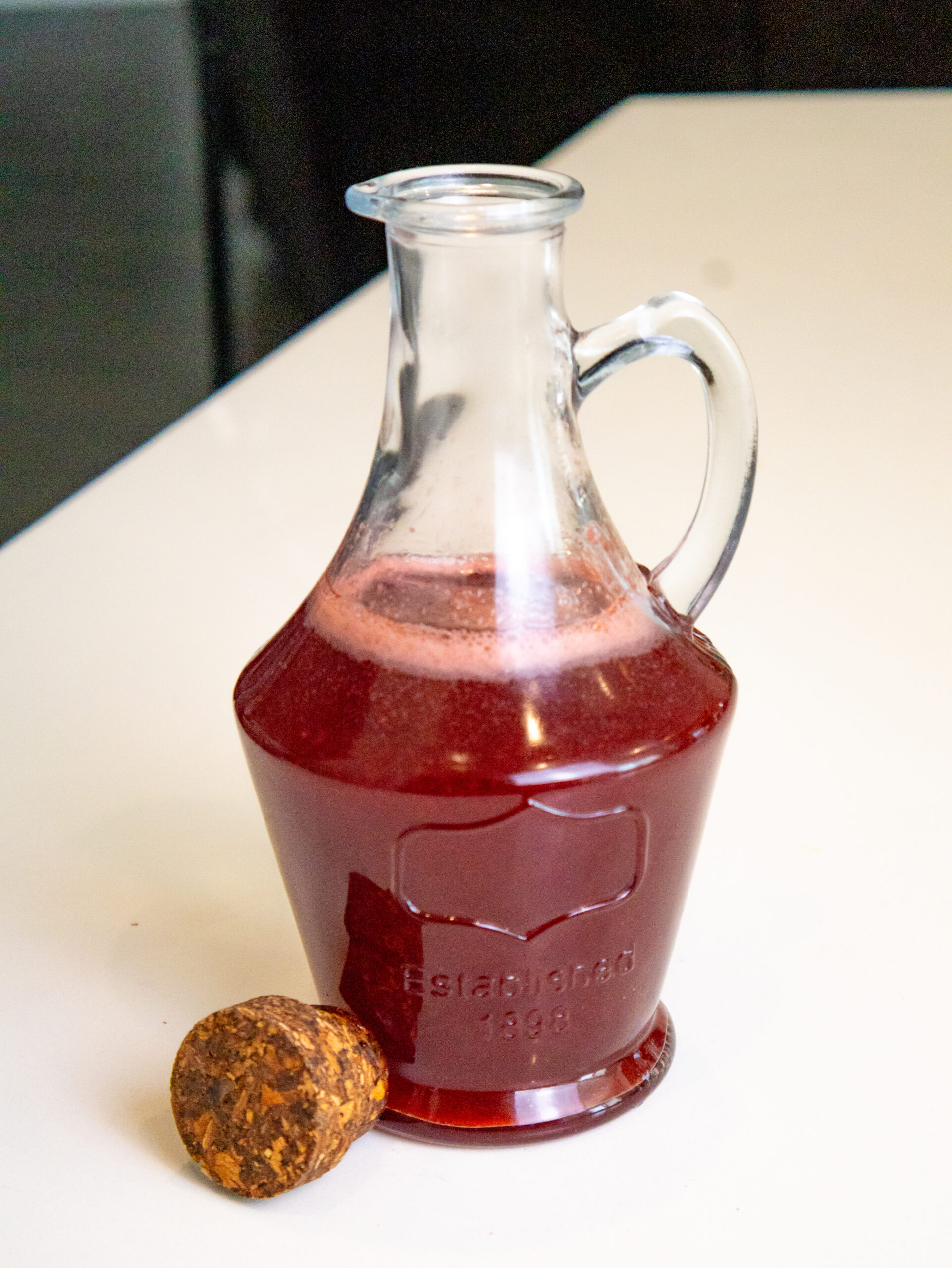 Homemade Strawberry Syrup in a bottle with a cork, prepared for use in the Strawberry Milk.